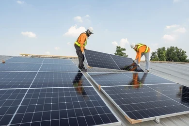 Operarios instalando paneles solares fotovoltaicos en un techo industrial